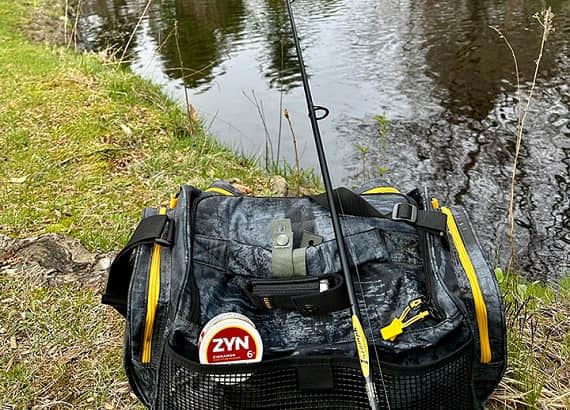 ZYN Cinnamon 6mg pouch placed next to a lure fishing rod