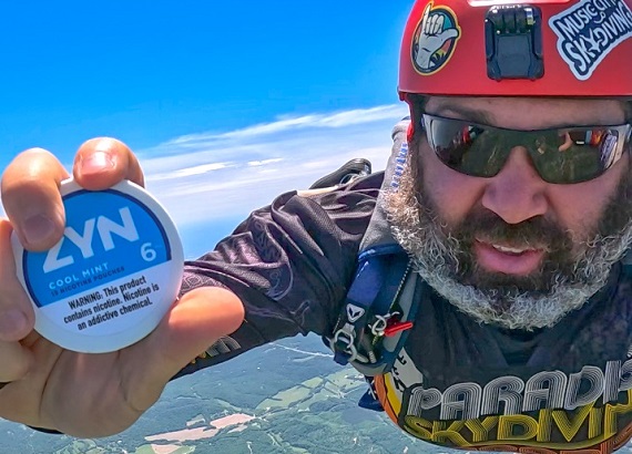 ZYN Cool Mint 6mg pouch held mid-air during a parachute jump